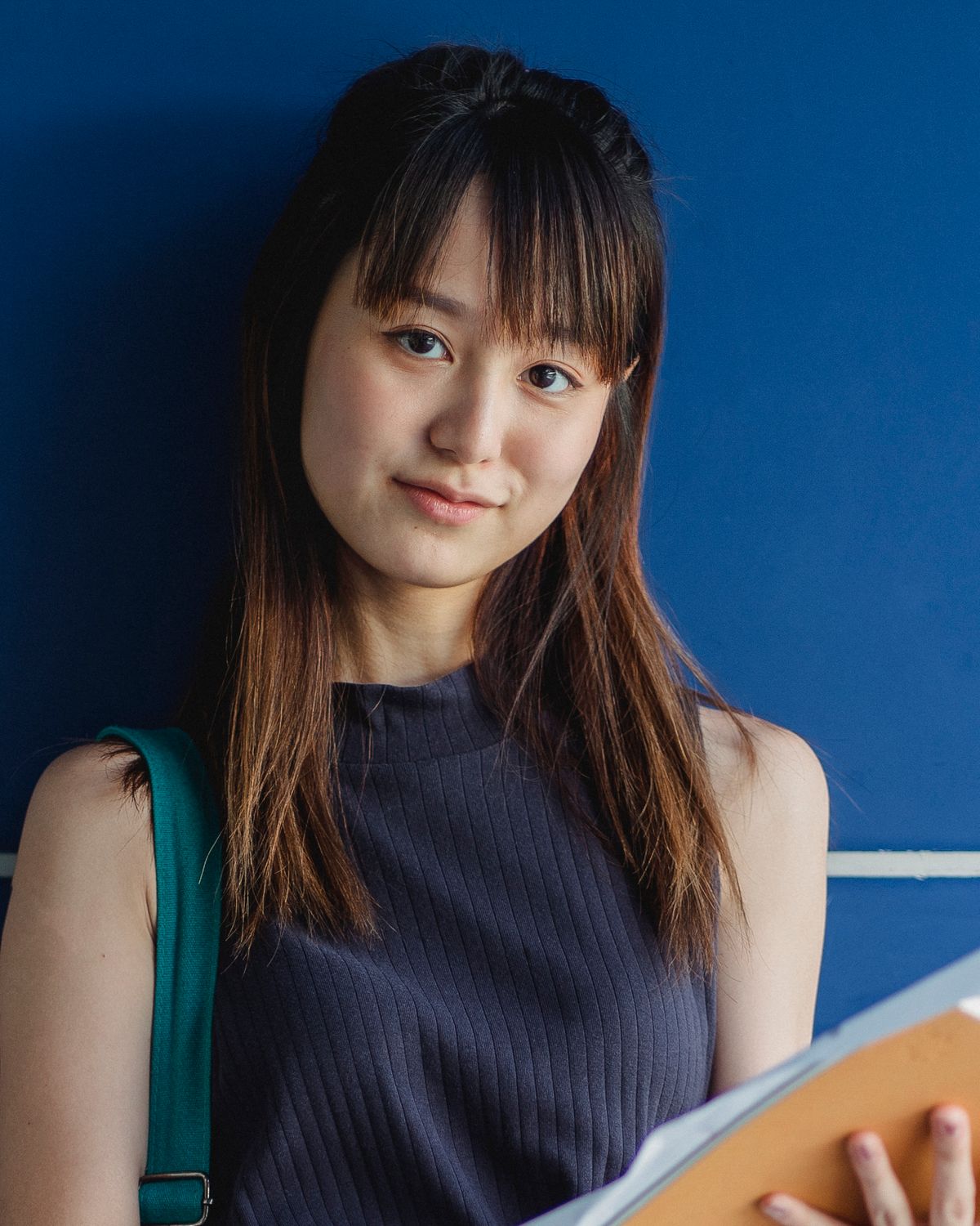A smiling international student holding a folder